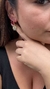 Imagem de uma mulher usando um brinco argola com pingente de olho grego cravejado de cristal, destacando a peça no ouvido. Banhado a ouro 18k. MW Semijoias