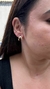 Brinco ear hook dourado em uma orelha feminina, destacando seu design elegante e moderno. Banhado a ouro 18. MW Semijoias