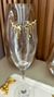 Brinco Ear Cuff Orgânico Cristal em formato orgânico, com detalhes em cristal, posicionado em uma taça de vidro. Banhado a ouro 18k. MW Semijoias e Acessórios