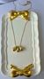 Colar semijoia com três gotas douradas penduradas em uma corrente fina, exibido em um prato decorativo com laços dourados. Banhado a ouro 18k. MW Semijoias e Acessórios