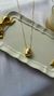 Colar semijoia em forma orgânica com pingente dourado sobre uma bandeja decorativa.