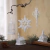 Colgante navideño de diseño elegante con copos de nieve, jaula y ornamentos blancos, decorando un ambiente festivo.