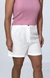 Modelo vestindo um short de alfaiataria branco com detalhe lateral, combinado com uma blusa rosa.