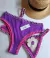 Biquíni roxo sob encomenda com detalhes em crochê rosa e flor decorativa, acompanhado de um chapéu de palha.