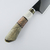 Detalle del mango de un cuchillo de acero inoxidable, con un diseño decorativo en tonos marrones y beige.