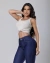 Modelo usando calça skinny azul escura e blusa cropped clara, posando com uma mão na cintura.
