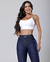 Modelo usando calça flare azul escura e top branco, sorrindo para a câmera.