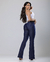 Modelo usando calça flare jeans escura, vista de costas, com blusa branca e acessórios elegantes.