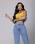 Modelo usando calça mom azul clara e blusa amarela, destacando a peça feminina.
