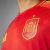 Camisa de treino da Seleção da Espanha, vermelha com detalhes em azul, destacando o escudo da equipe.