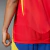 Detalhe da camisa de treino da Seleção da Espanha, mostrando a parte traseira vermelha com detalhes em azul e amarelo.