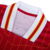 Detalhe do colarinho da camisa vermelha do Liverpool, modelo 24/25, com listras brancas e amarelas.