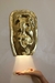 Arandela de cerâmica com banho dourado iluminando uma mão.