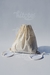 Mochila de lienzo color natural con cordón ajustable sobre fondo blanco