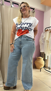 Mujer posando con jeans Eve Wide Leg rígido y una camiseta blanca con estampado, en un ambiente de tienda.
