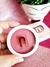 Blush compacto cor Barbie Nina Make Up em embalagem redonda branca, sendo segurado por uma mão sobre fundo rosa brilhante com vaso decorativo branco ao fundo
