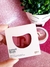 Blush compacto Instant Blush cor Barbie da Nina Make Up em embalagem rosa clara com detalhes em vermelho, segurado por uma mão sobre fundo rosa brilhante, ao lado de um vaso decorativo com plantas.