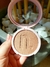 Blush compacto Instant Blush cor Coral Nina Make Up aberto sendo segurado à mão, com embalagem rosa claro e espelho interno refletindo fundo de pedras brancas