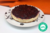 Cheesecake Low Carb de Frutos Rojos en un plato blanco con diseño negro, sobre fondo naranja.