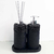 Essenza Volcano Lavatory Kit featuring two black stone-like containers with a pump dispenser and reed sticks on a tray.