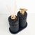 Essenza Volcano Lavatory Kit featuring a black stone holder with a soap dispenser and reed diffuser sticks.