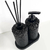 Essenza Volcano Lavatory Kit featuring two black containers with a textured finish, a pump dispenser, and reed sticks.
