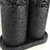 Close-up view of the Essenza Volcano Lavatory Kit featuring two textured black cylindrical containers on a base.