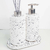 Kit lavabo Milão composto por dois dispensers e suporte, com design em material branco com manchas pretas.