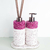 Conjunto de acessórios de lavabo com dispensador e difusor, decorados com pedras rosas e base branca.