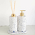 Conjunto de kit lavabo Safira com dois recipientes brancos, um com bomba dourada e outro com varetas de difusor, sobre uma bandeja.