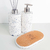 Conjunto de itens para lavabo, incluindo dois frascos brancos com detalhes em azul e um suporte de cortiça.