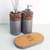 Kit de aseo Pekín con dispensador de jabón y frasco de aromatizante, decorados con piedras pequeñas y base de corcho.