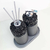 Kit Lavabo Tóquio com design sofisticado, composto por dois dispenseres com detalhes em pedras pretas e uma bandeja cinza.