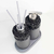 Conjunto de itens de lavabo com design moderno, incluindo um dispenser e um recipiente, ambos com acabamento em pedras pretas e detalhes em metal.
