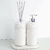 Kit Lavabo Santorini com dois dispensers em tons claros, decorados com pedras brancas e acompanhados de um suporte.