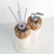 Kit lavabo Duna com design elegante, composto por dois dispensadores decorativos com pedras naturais e canudos de papel.