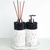 Conjunto de acessórios de banheiro estilo moderno, com suporte para sabonete líquido e difusor de aromas em pedra branca e detalhes pretos.
