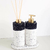Kit Lavabo Paris com dois dispensers, um para sabonete e outro para difusor, ambos com base branca e detalhes em preto e dourado.