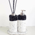 Conjunto de acessórios para lavabo com dispenser e difusor, ambos com base em textura clara e detalhe em preto.