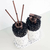 Conjunto de itens para lavabo com dois frascos decorativos, um com bomba e outro com varetas, ambos com base de material claro e detalhes em pedras pretas.