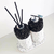 Kit Lavabo Paris composto por frascos decorativos com tampa prateada e palitos de difusor, com base em design moderno e elegante.