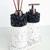 Conjunto de itens de lavabo com frasco de sabonete e difusor, ambos com base branca e detalhes em pedras negras.