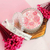 Aurora Candle in a glass container featuring pink rose designs, accompanied by pink dried flowers.