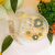Vela Aurora de Mel e Limão decorada com flores em um recipiente de vidro.