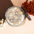 Vela aromática Skye com flores decorativas em um recipiente de vidro, ao lado de flores secas.