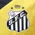 Detalhe do escudo do Santos FC na camisa amarela e preta, modelo 24/25, da Umbro.