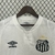 Camisa branca do Santos Futebol Clube com o logo da Umbro e detalhes em preto, exibindo a sigla S.F.C. e duas estrelas acima do escudo.