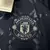 Logotipo bordado do Manchester United em uma camisa azul escuro da Adidas para torcedores, temporada 24/25.