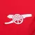 Emblema do Arsenal em bordado branco sobre fundo vermelho da camisa de torcedor Adidas.