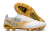 A pair of white and gold soccer cleats featuring a lion graphic design and a textured sole for grip.